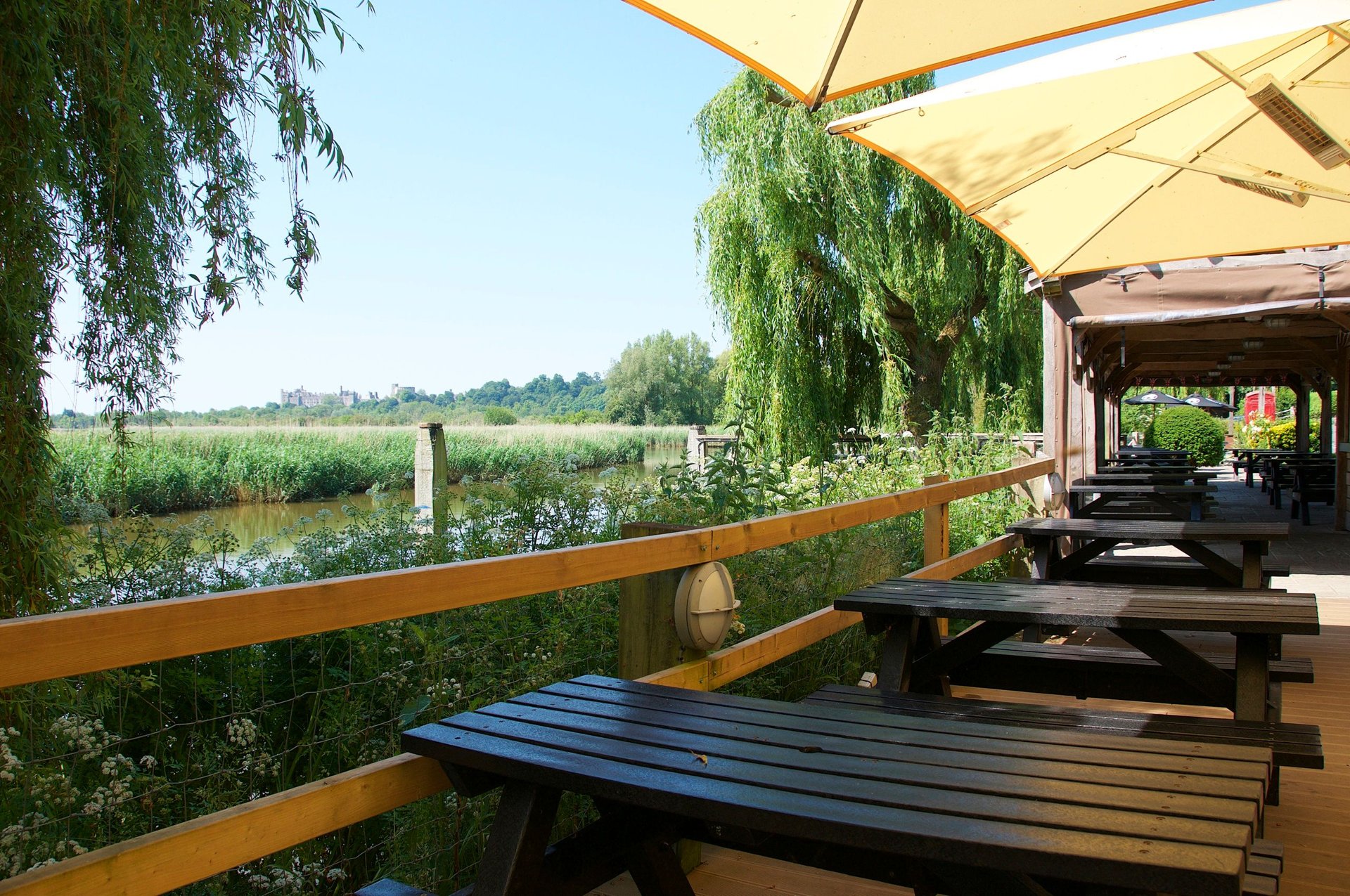 Benches on The Black Rabbit’s riverside terrace, looking across the reeds of the River Arun towards Arundel Castle