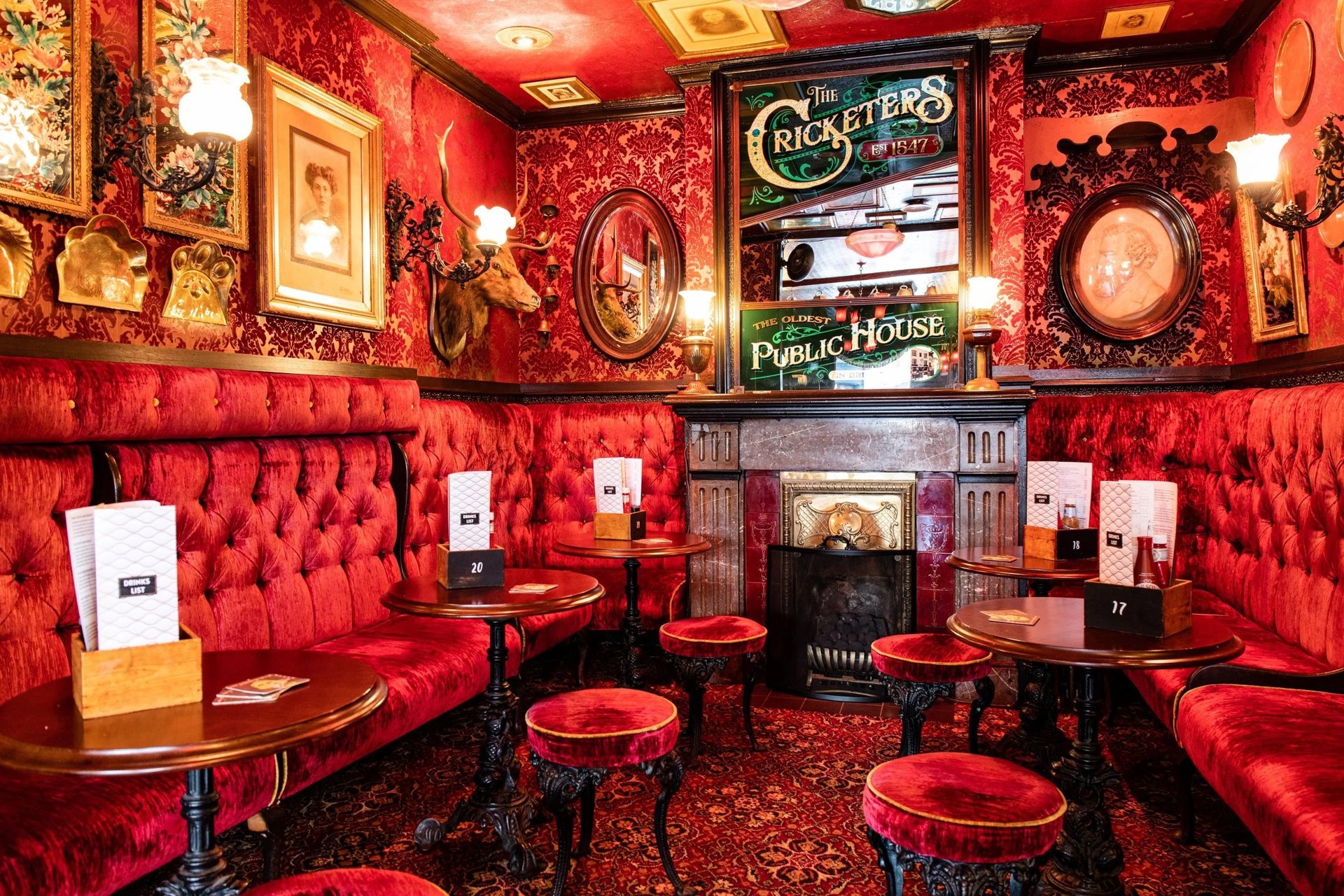 The red velvet banquettes, mirrors and fireplace inside The Cricketers