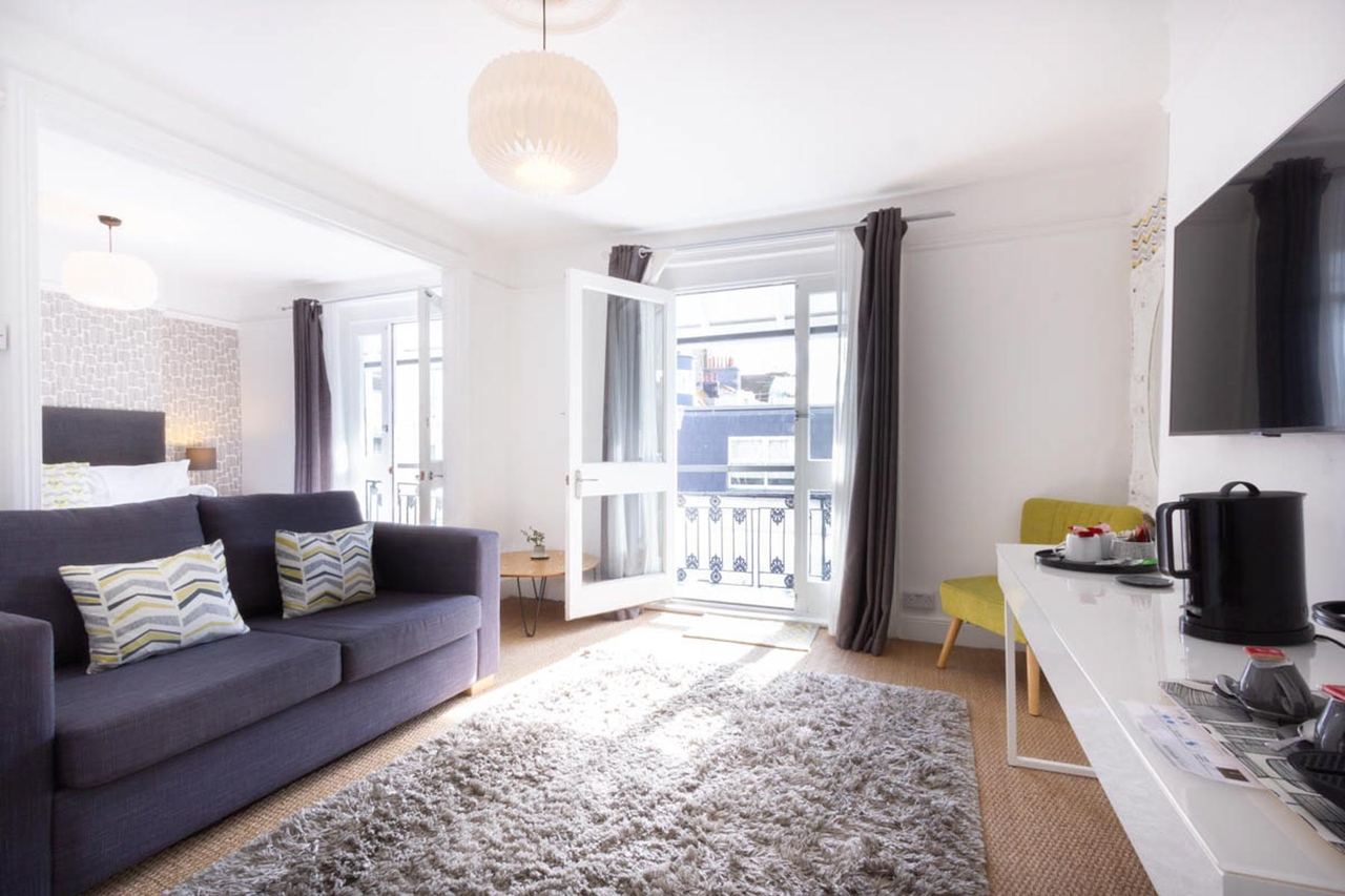 A light room at The White House with a sofa, a rug and French windows to a balcony