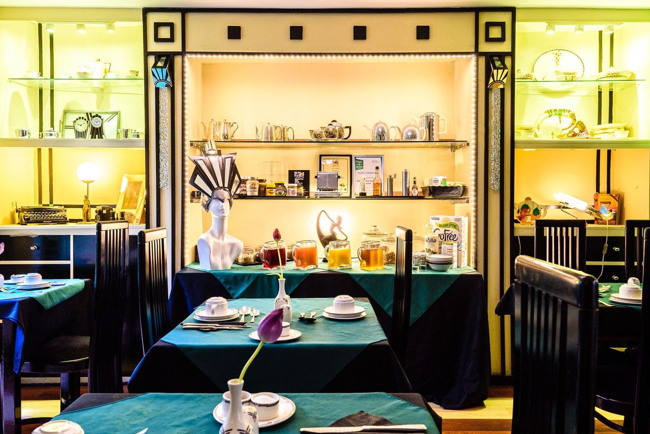 The Art Deco breakfast room at Paskins Town House, with green tablecloths and lit shelves