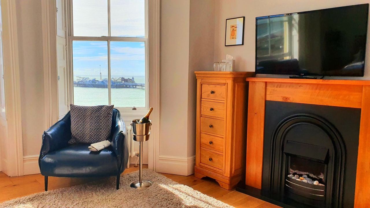 A room at A Room With A View with a leather armchair by the window and the Palace Pier beyond