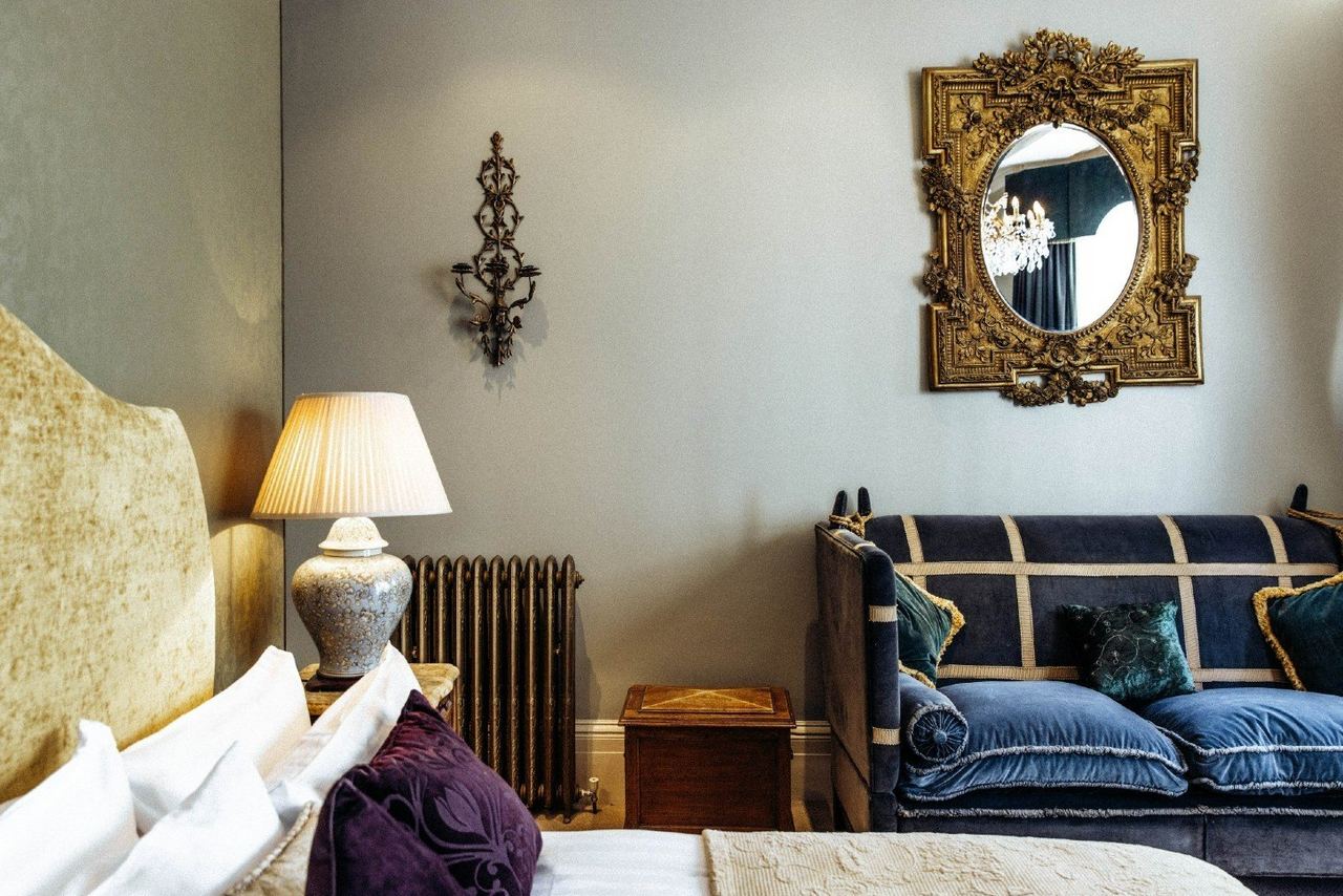 A bedroom at Blanch House with a gilt mirror, a velvet sofa and a lamp