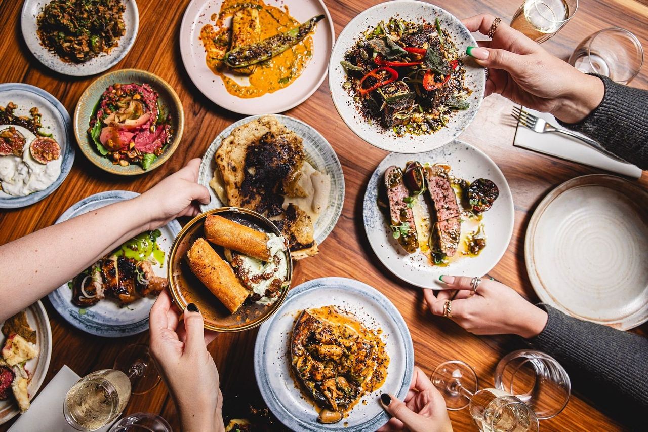 Sharing plates of fire-cooked food on a wooden table at The Coal Shed