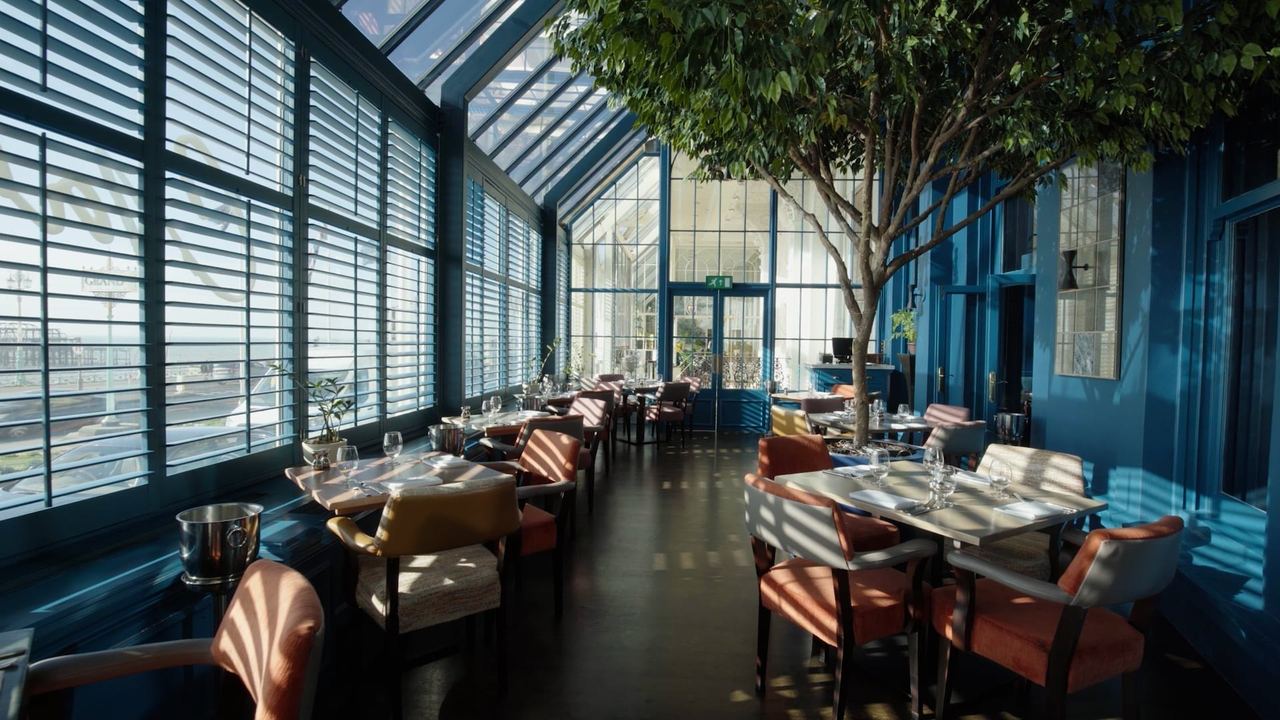 The glazed dining room of Cyan at The Grand, with blinds, a tree and blue walls