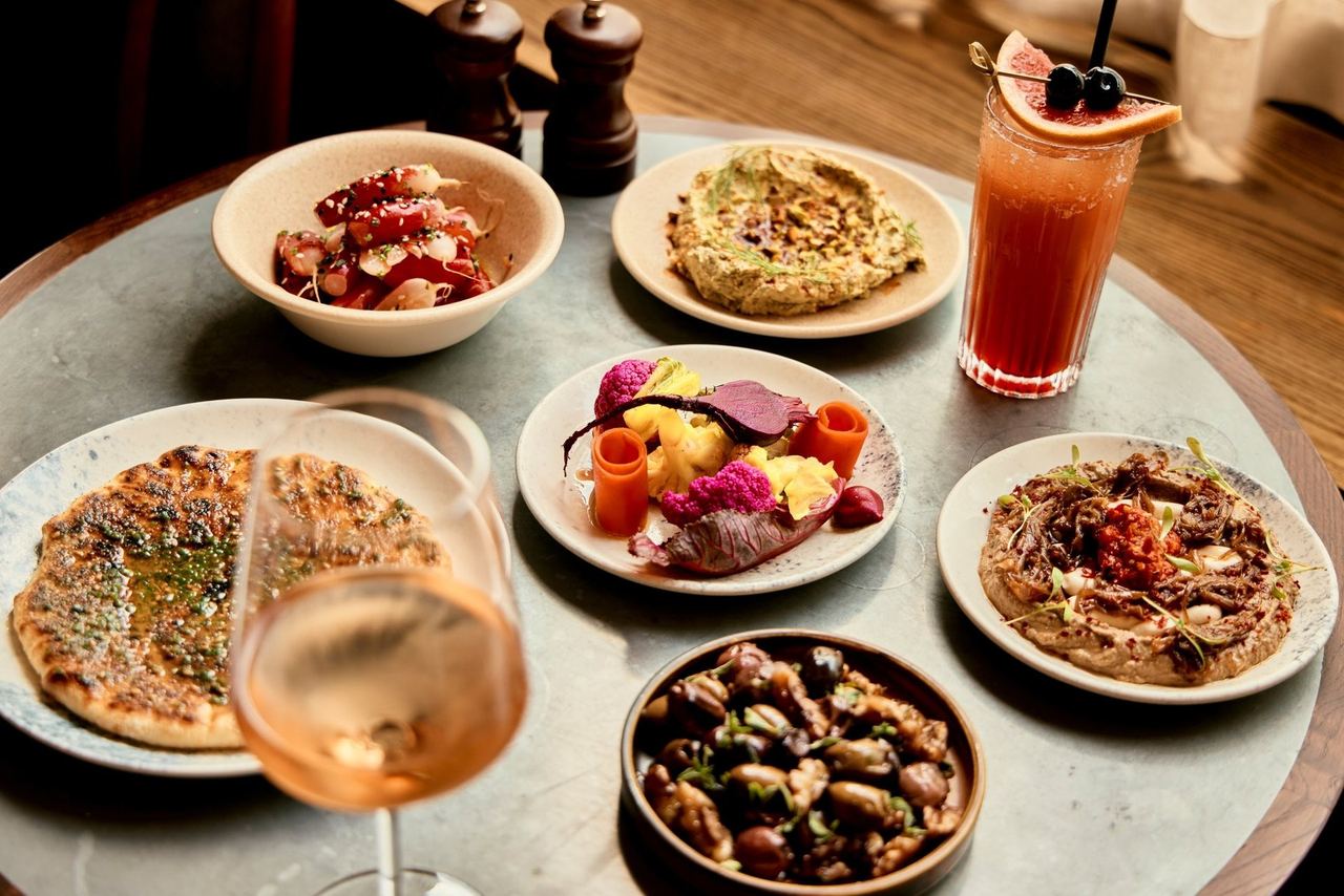 Small plates and a cocktail on a round table at The Crazy Goose
