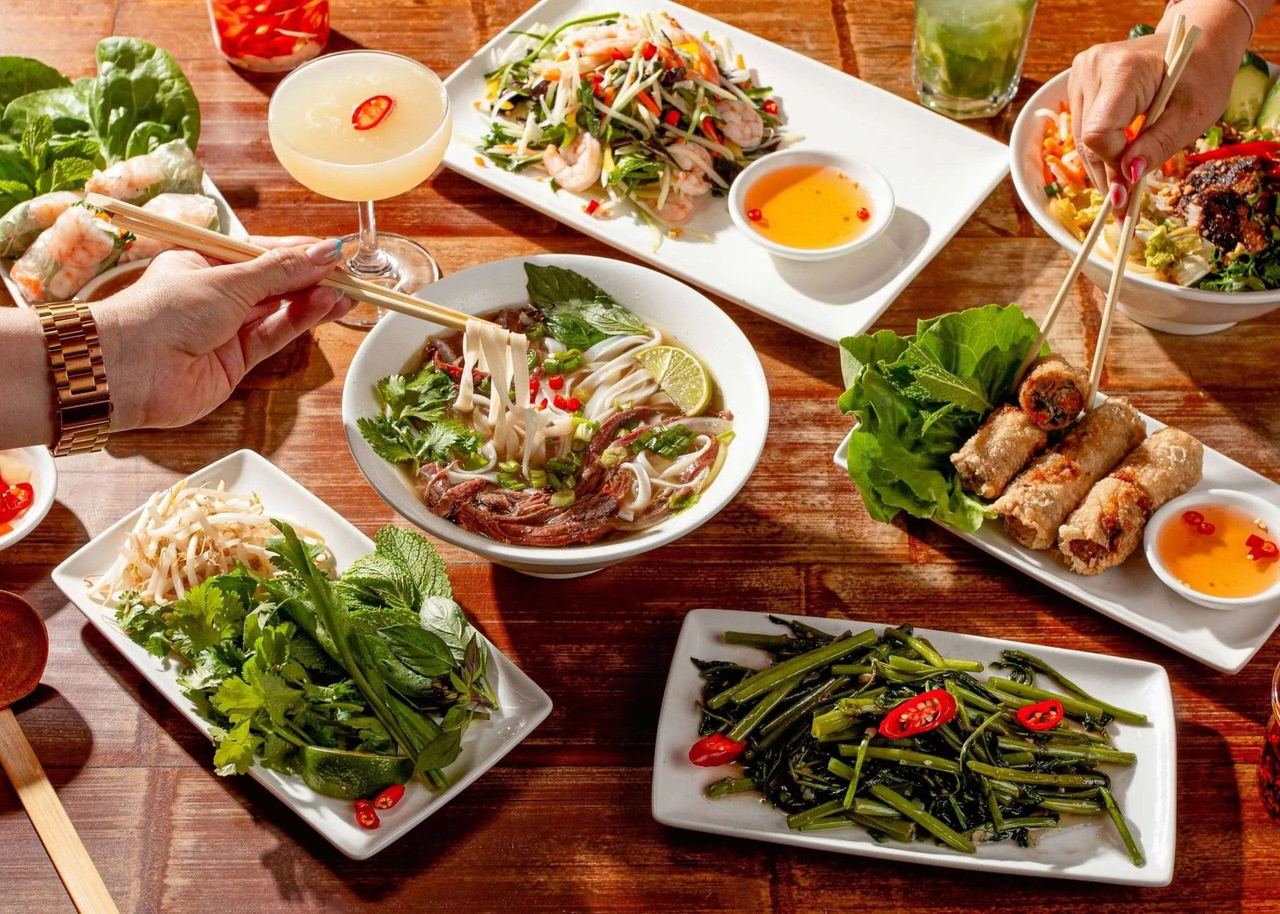 Pho, summer rolls and greens on a table at Pho