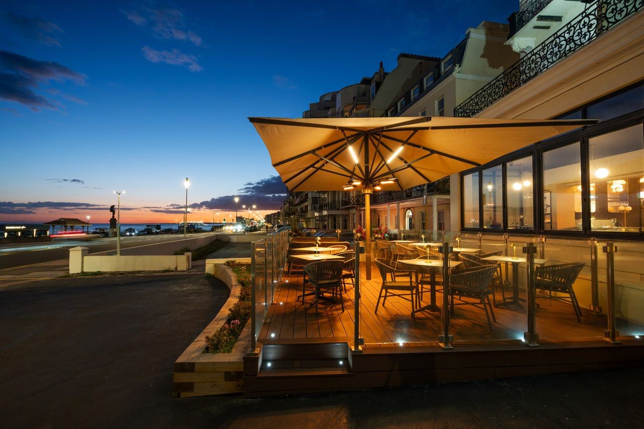 Coastal’s glass-screened terrace on the seafront at dusk