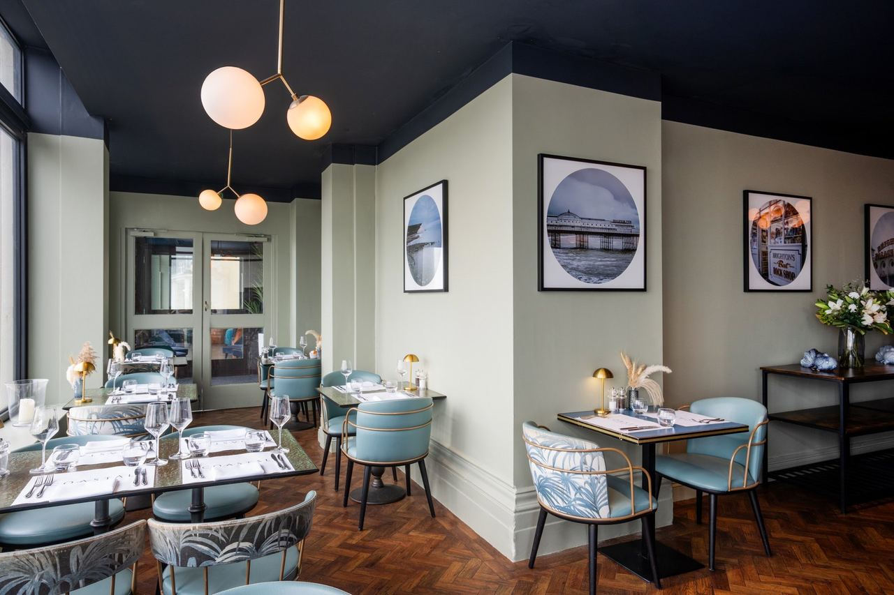 The dining room of Coastal, with globe lights and blue chairs