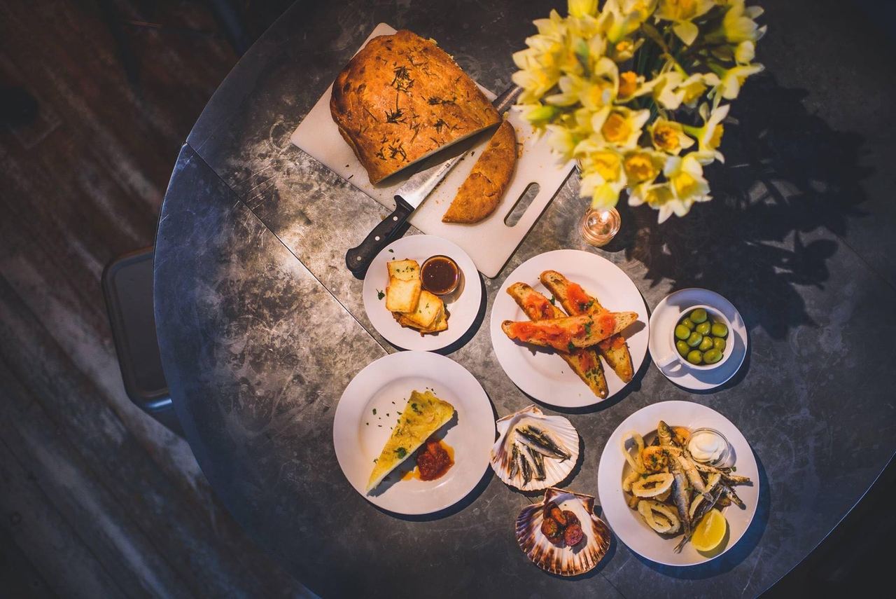 Tapas, focaccia and daffodils on a round table at Seed