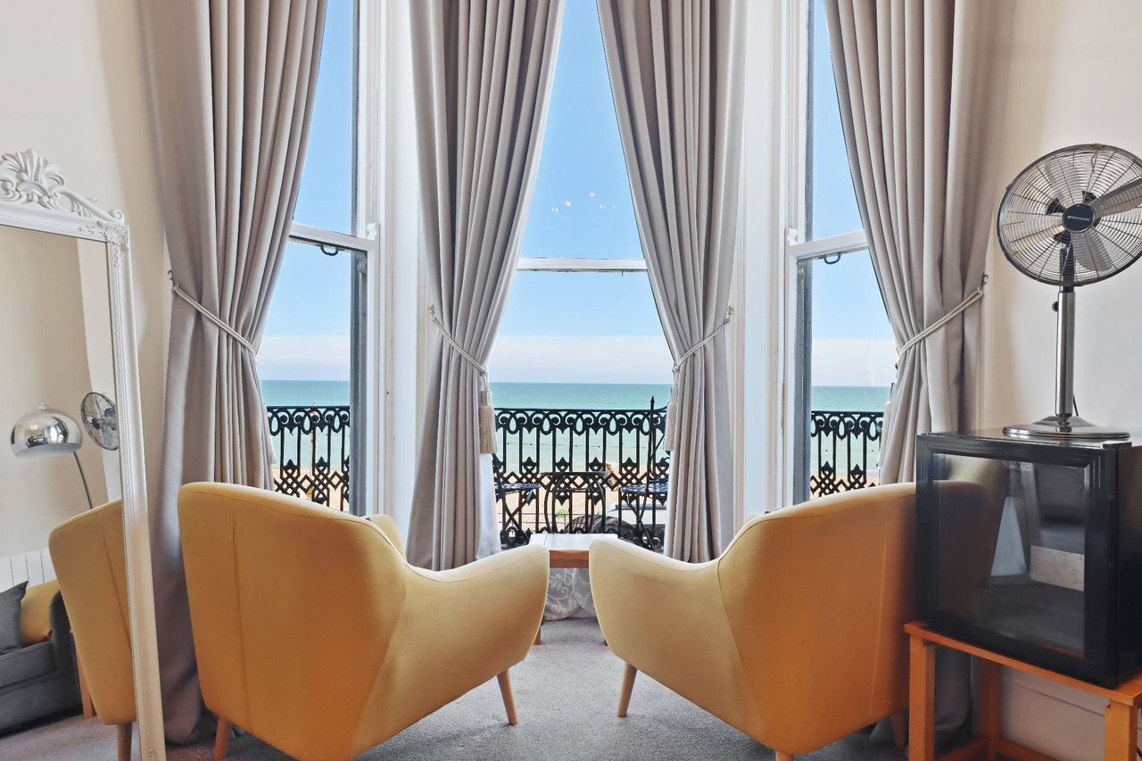 Two yellow armchairs in the bay window of a sea-view room at Beach Front Guest House