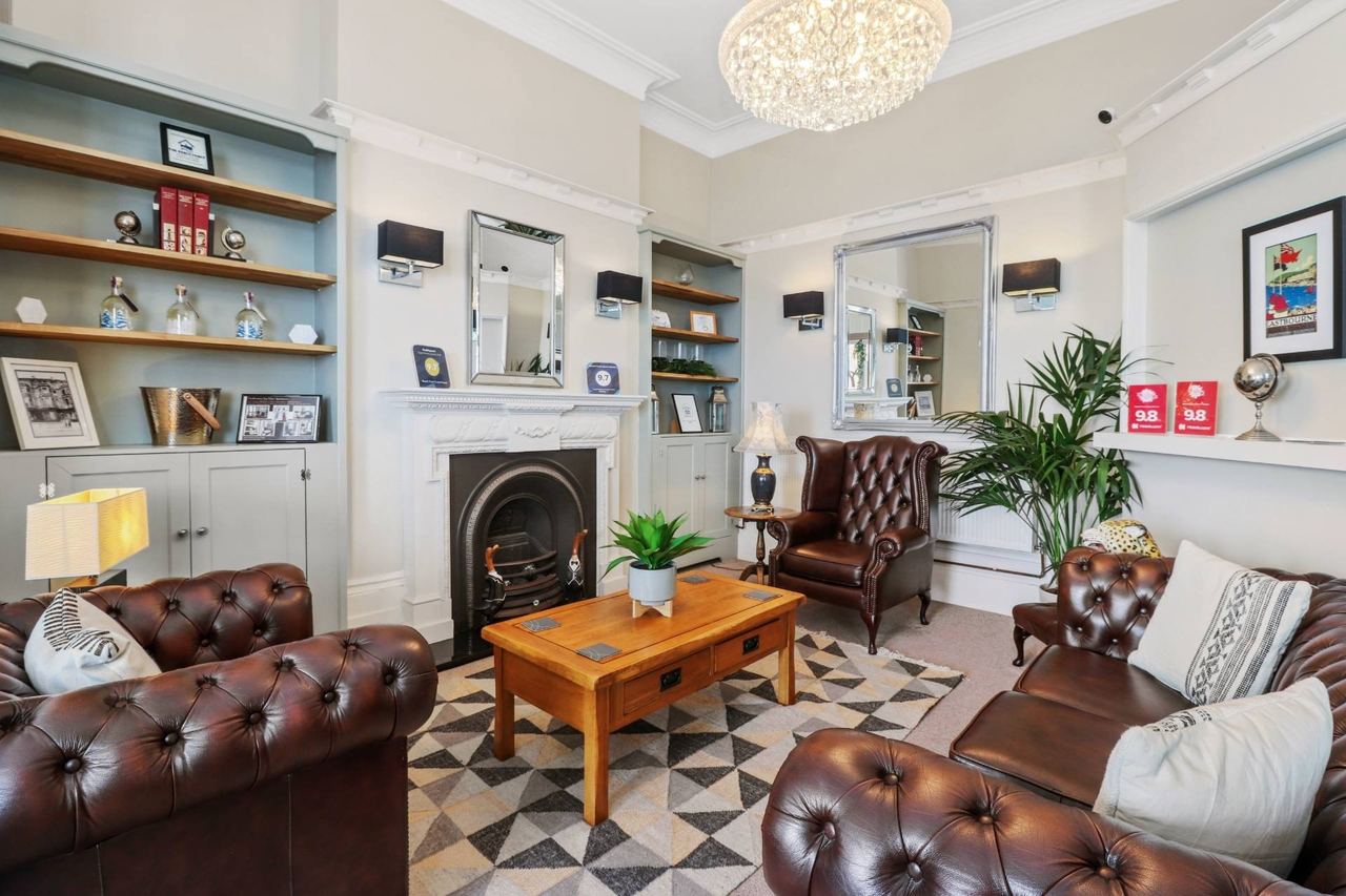 The lounge at Beach Front Guest House, with leather Chesterfields and a cast-iron fireplace