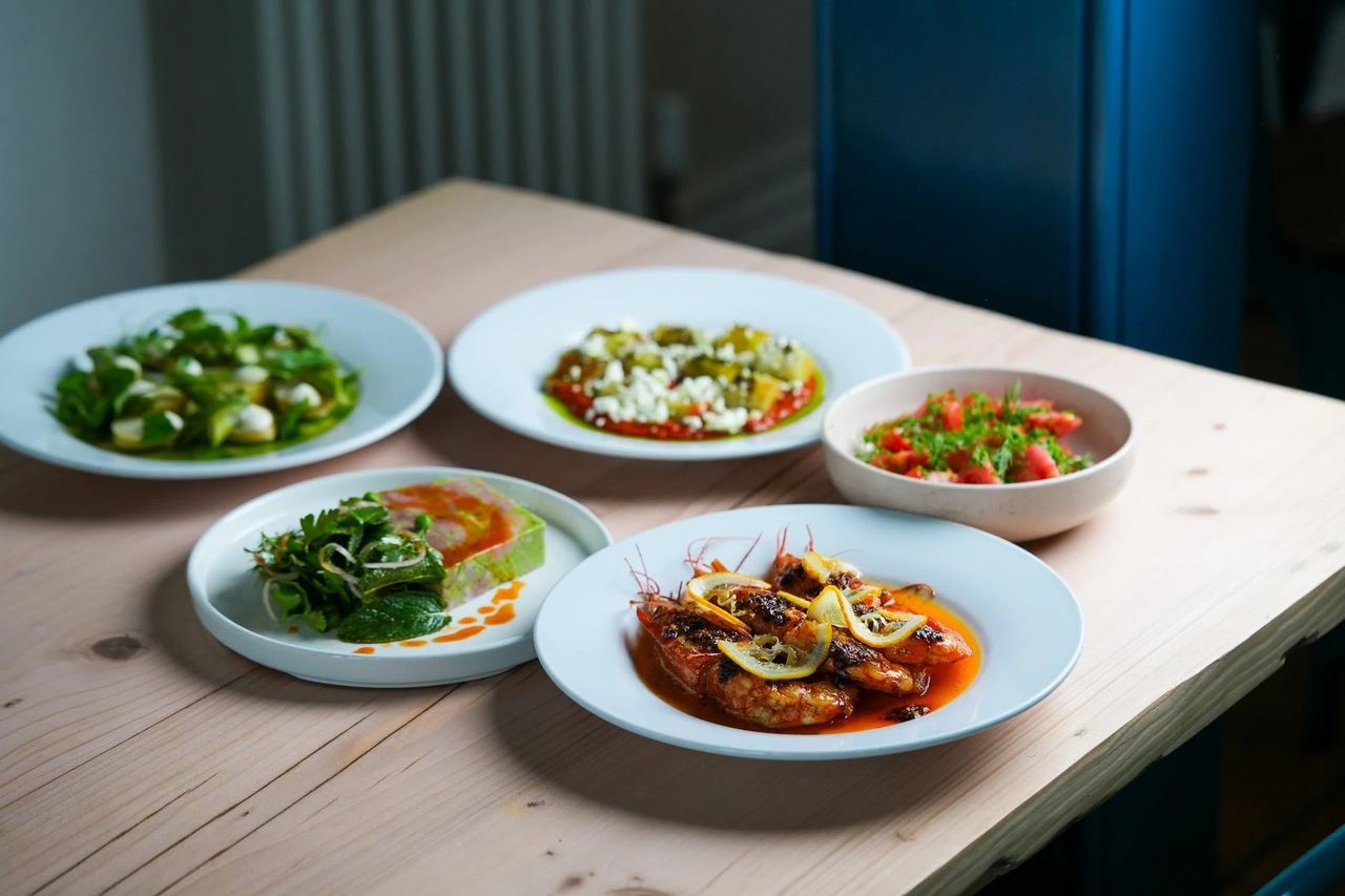 Seasonal small plates and grilled prawns on a pale wooden table at Skylark