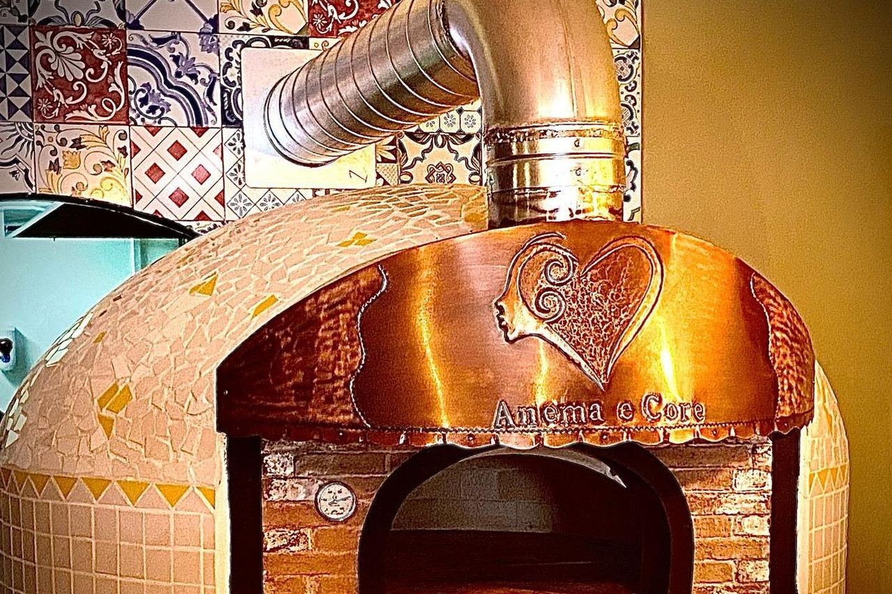 The copper-fronted wood-fired pizza oven at Trattoria Anema e Core