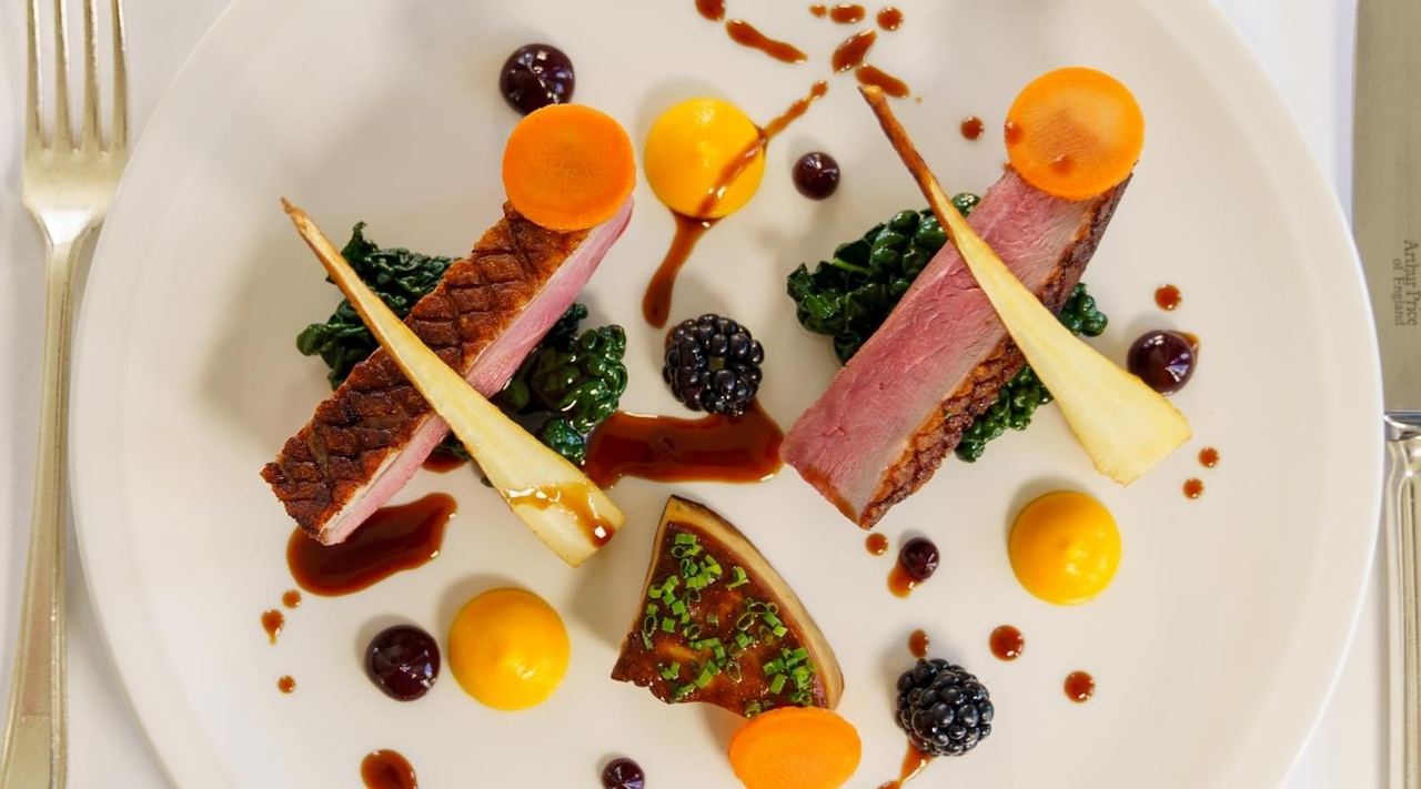 A plated dish of duck with root vegetables and blackberries at the Mirabelle