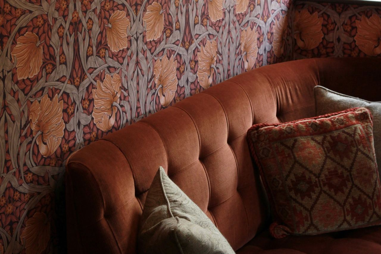 A velvet banquette against William Morris-style wallpaper at The Bohemian