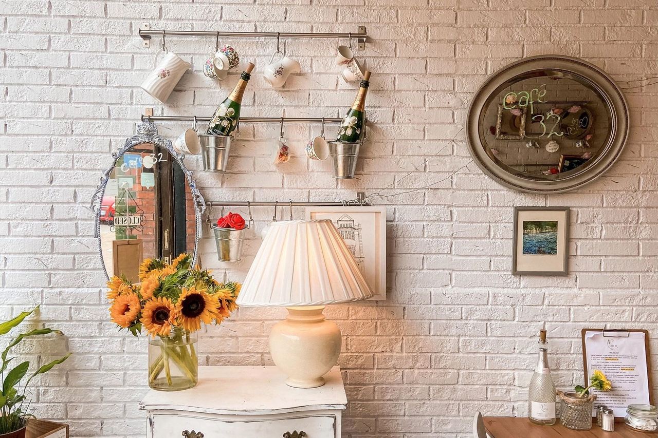 Sunflowers, vintage cups and a painted chest against white brick at Café 32